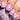 Close-up of a hand with pink nail polish holding a pink nail polish bottle.