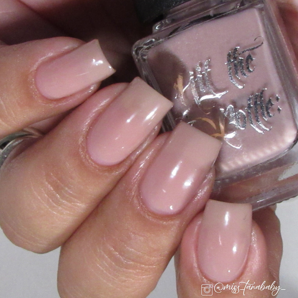 Hand with pink nail polish holding a bottle of Hit the Bottle nail polish.