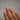 Hand with nude-colored nail polish on a plain background