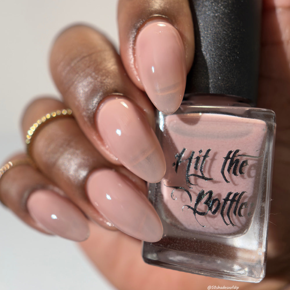 Nail polish bottle with 'Hit the Bottle' text held by a hand with pink nail polish.