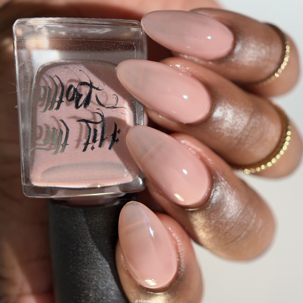 Nail polish bottle with a hand displaying nails painted with a soft neutral pink.