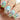 blue to green pastel gradient, with spring flowers, a bunny in a cup and easter eggs
