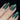 Nail polish with a glittery green and blue color on a black background