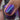 Close-up of a hand with purple glittery nail polish holding a bottle of nail polish.