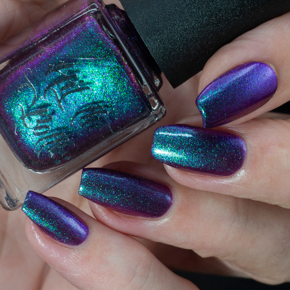 Nail polish with a metallic purple and green design held by a hand with matching nails.