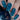 Nails with blue geometric pattern held above a bottle of nail polish.