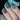Nails with geometric pattern held against a dark background
