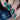 Nails with green and blue patterned nail art held against a dark background