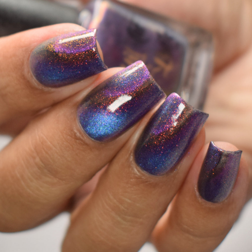 Close-up of a hand with purple and blue glittery nail polish.