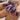Close-up of a hand with purple and blue glittery nail polish.