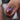 Close-up of a hand with glittery nail polish and a bottle of nail polish in the foreground.