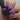 Hand with purple nail polish holding a bottle of nail polish