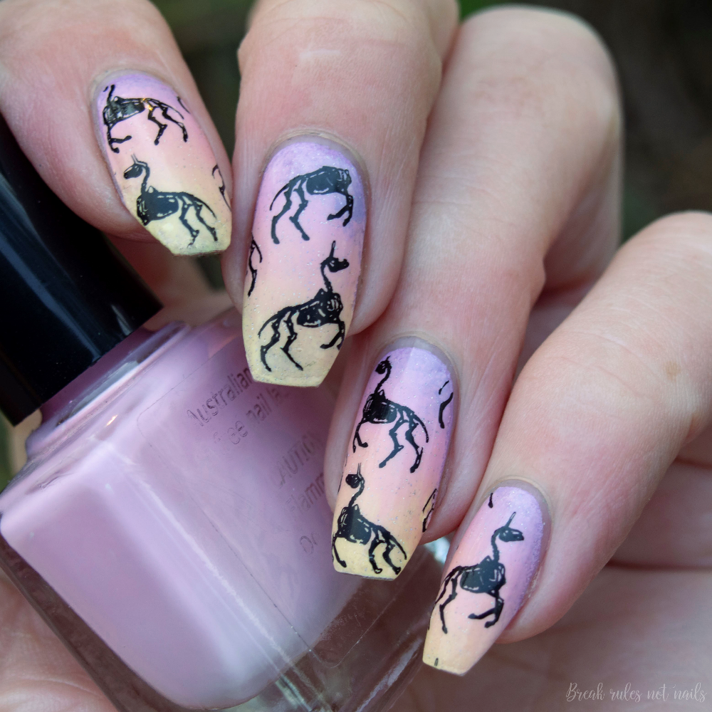 Purple, pink, apricot and lemon pastel gradient base. Black stamping of unicorn skeletons. Whole hand